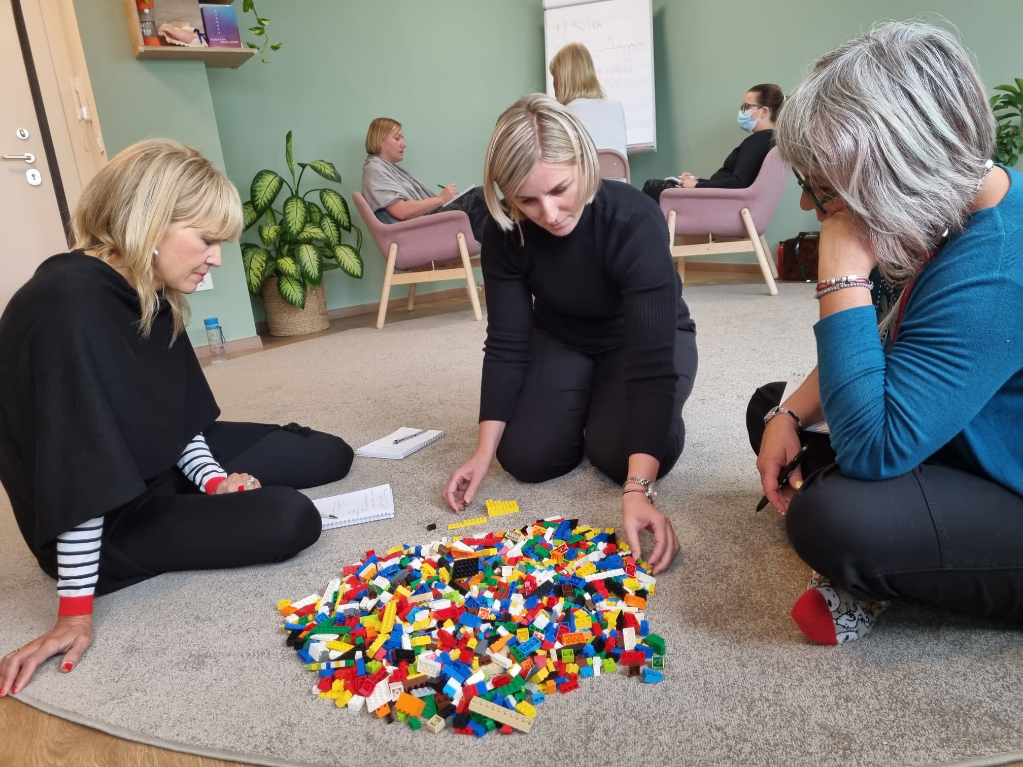 Grupa žena zajedno slaže LEGO kockice — timski rad i izgradnja prakse